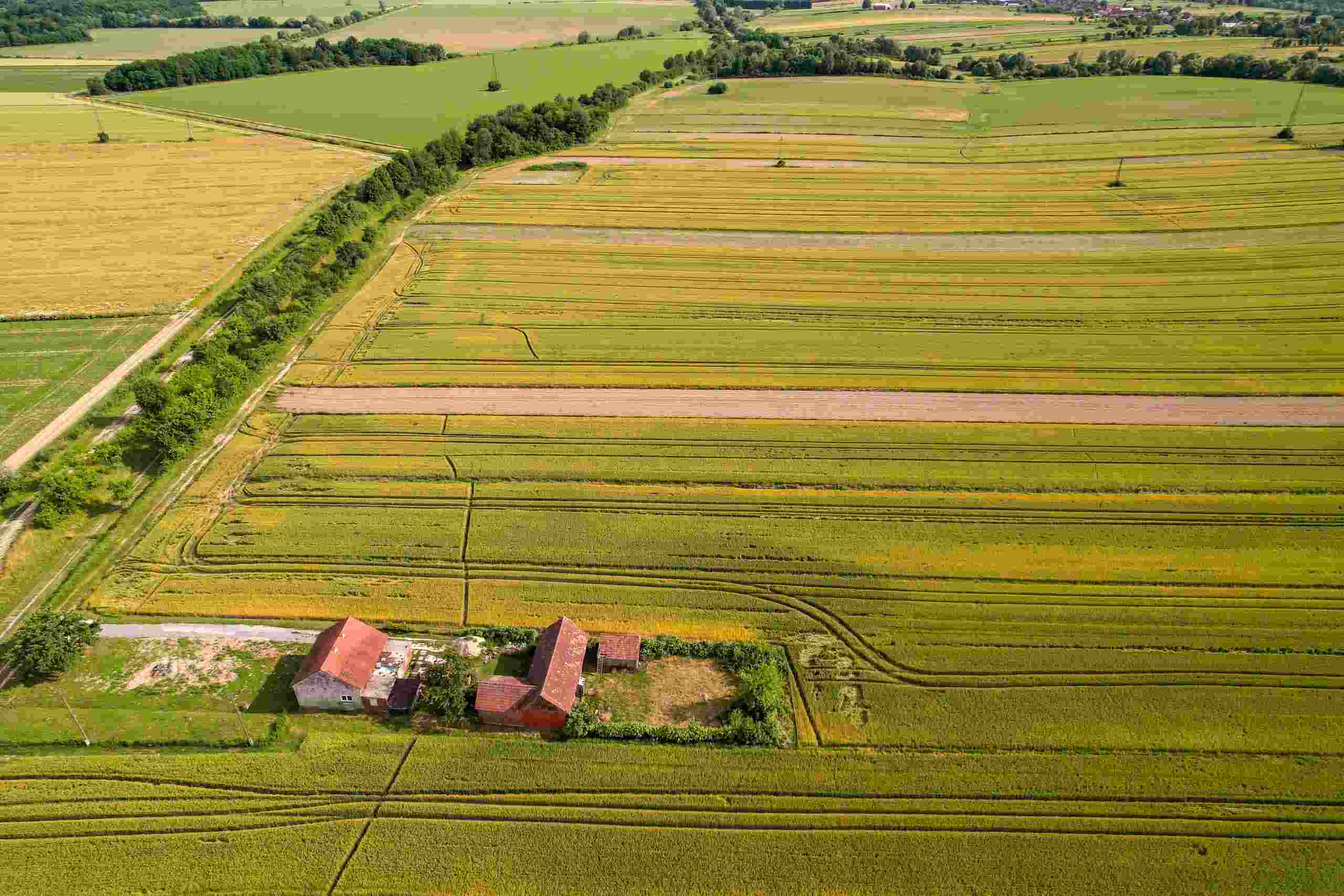Aerial view of farmland and farm buildings representing Tractor financing, ranch land loans, fertilizer financing, agricultural water infrastructure financing, and wind turbine financing for agricultural operations.