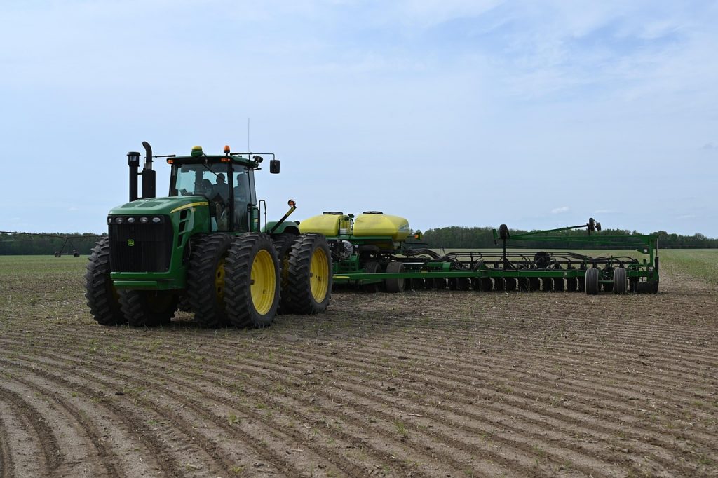 Large tractor pulling a precision planter across cultivated farmland, representing Hay baler financing, farm property loans, cattle financing, grain cart financing, and forage harvester financing that help farmers invest in modern equipment, farmland, livestock, and efficient harvesting operations.